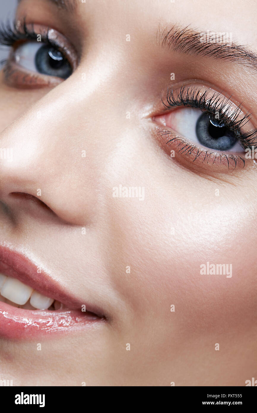 Closeup macro shot of smiling female face and eyes beauty makeup. Woman with glossy glitter white skin. Stock Photo