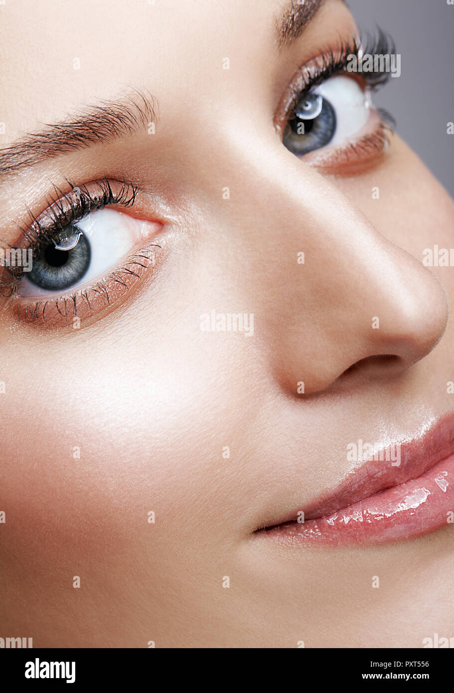 Closeup macro shot of smiling female face and eyes beauty makeup. Woman with glossy glitter white skin. Stock Photo