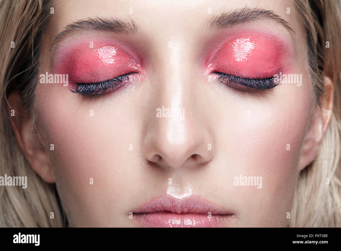 Closeup macro shot of female face and pink smoky eyes beauty makeup. Woman with glossy glitter white skin. Stock Photo