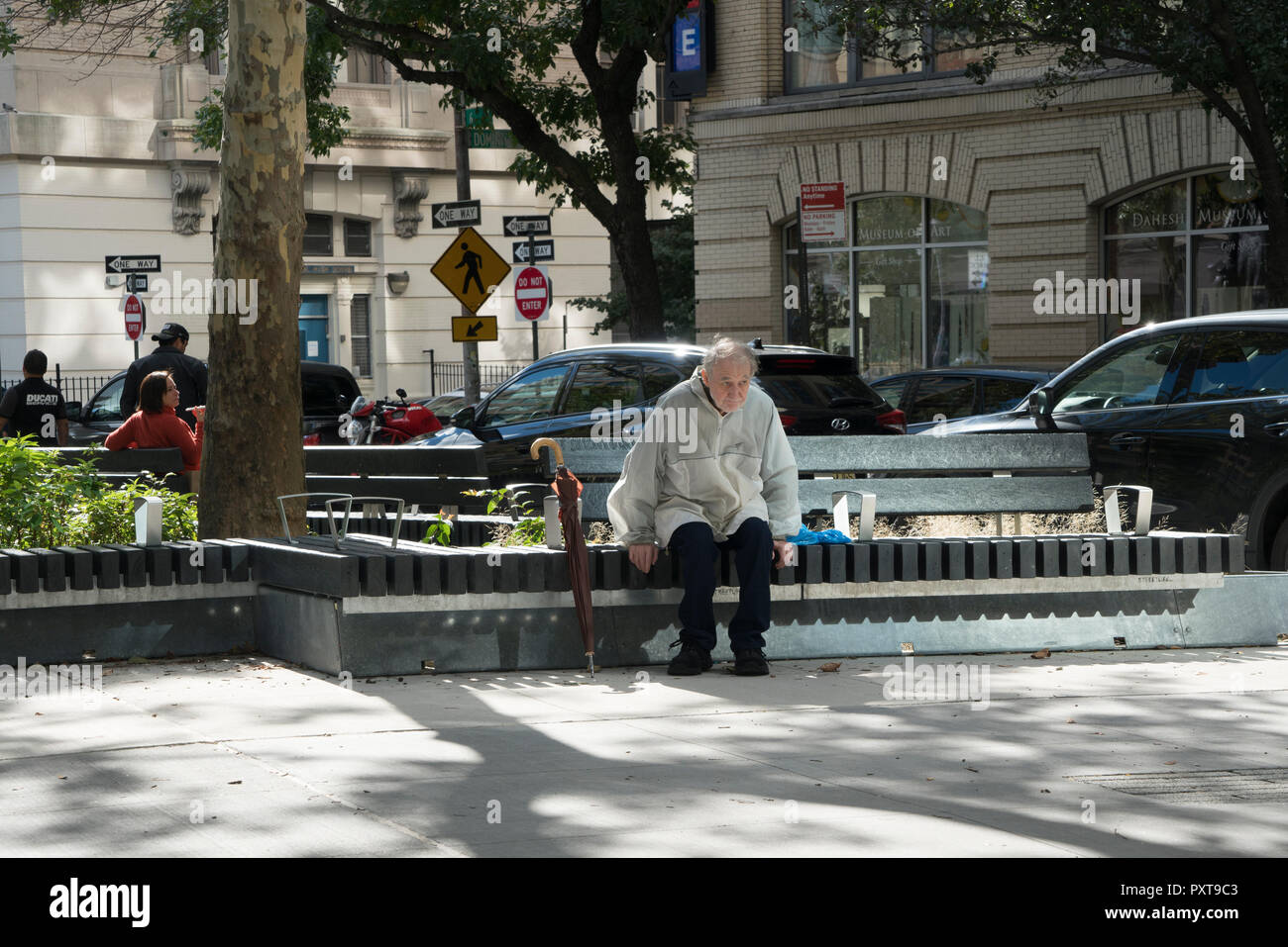 An elderly man with an umbrella sat alone in the Spring Street Park on a sunny day in October. The park, which is just under an acre in size, is south Stock Photo