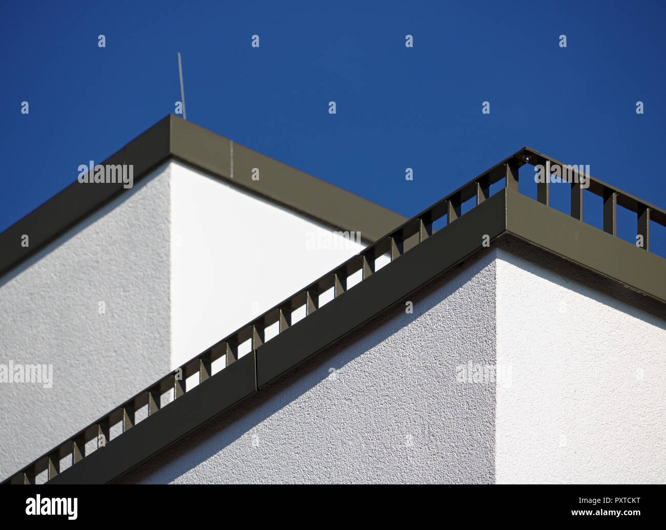 Corner of a white building with diagonal balcony railing and blue sky Stock Photo