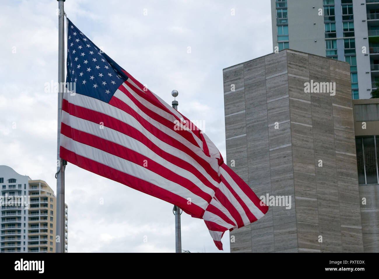 Two american flags waiving on wind on bright cityscape background Stock Photo