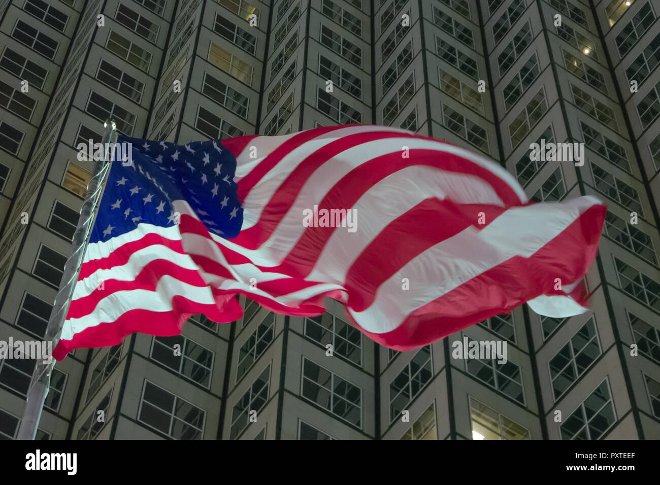 USA flag in front of business building at night Stock Photo