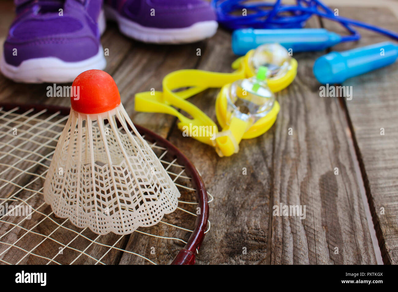 Sports equipment: the birdie is on the racket, skipping rope, swimming  goggles and sneakers on wooden background Stock Photo - Alamy
