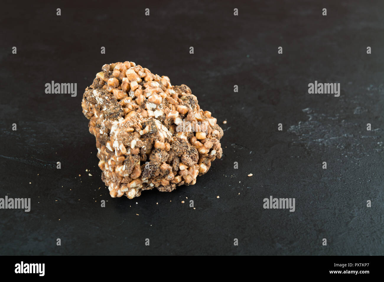 One piece of milk chocolate with puffed rice and raisins over black