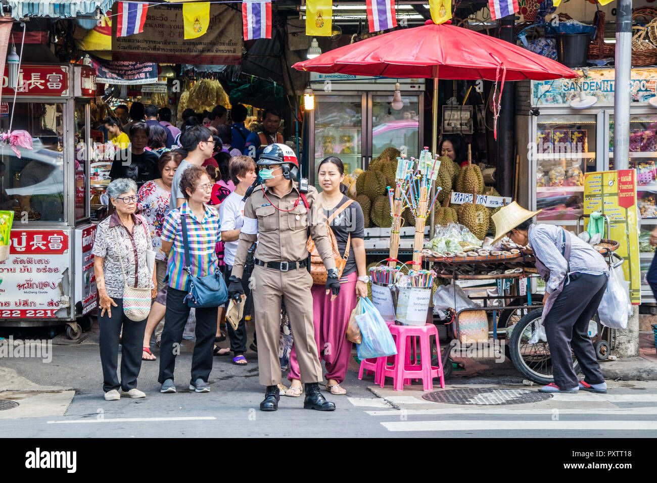 Bangkok, Thailand - 25th September 2018: A policeman controls traffic at a zebra crossing. Yaowarat road is the main thoroughfare in Chinatown. Stock Photo