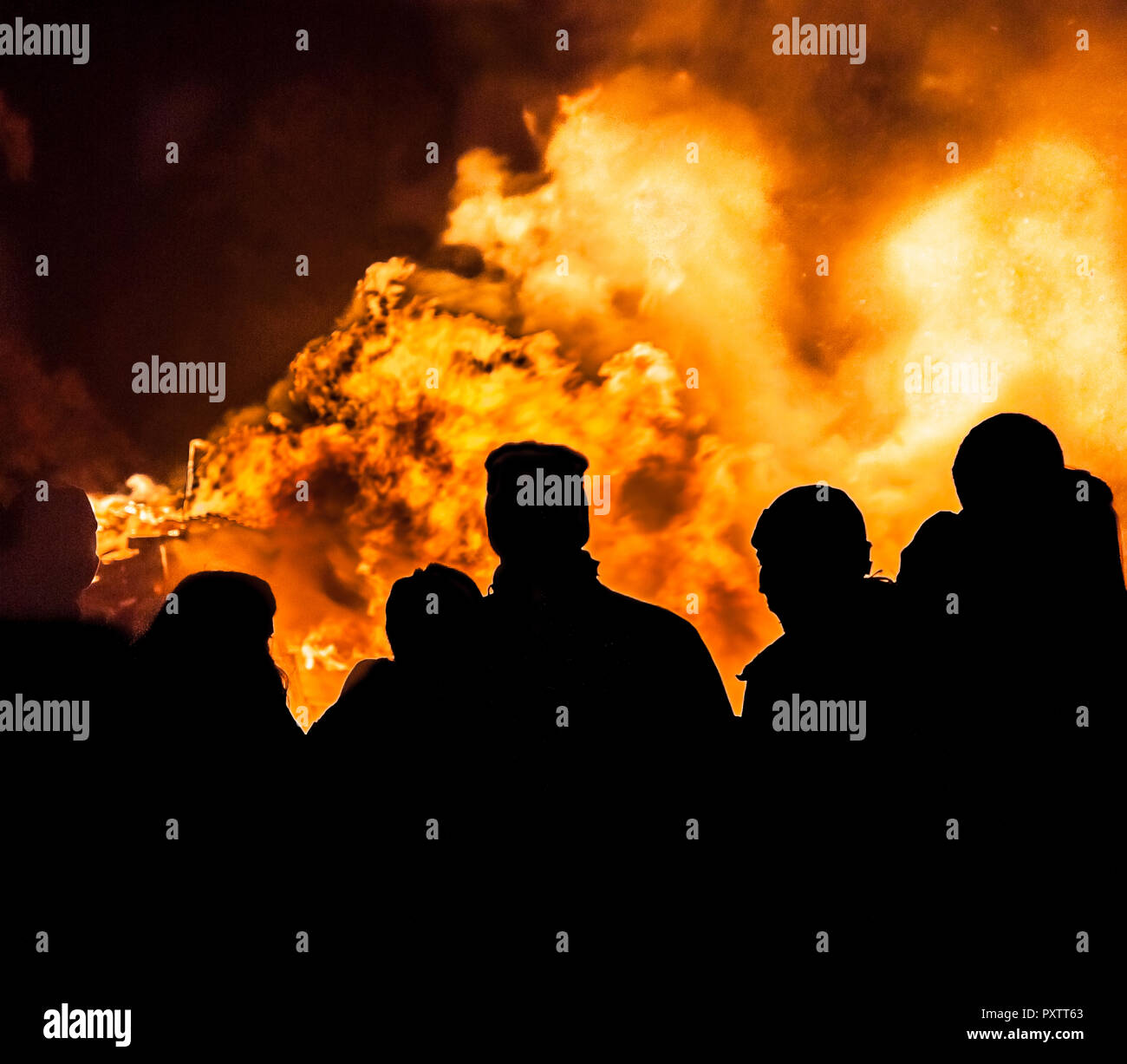 A gathering of people silhouetted against a burning bonfire on November the 5th. Stock Photo