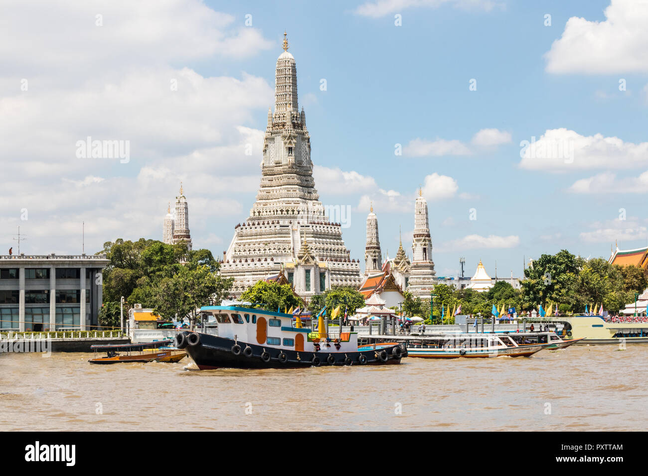 A tug boat trundles past the Temple of Dawn, Wat Arun on the Chao Phraya river, Bangkok, Thailand Stock Photo