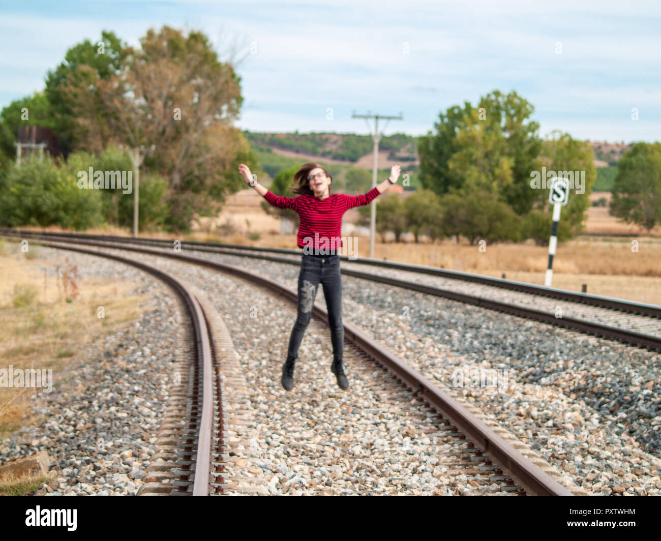A teenage girl jumping on the train tracks. Concept of freedom and joy