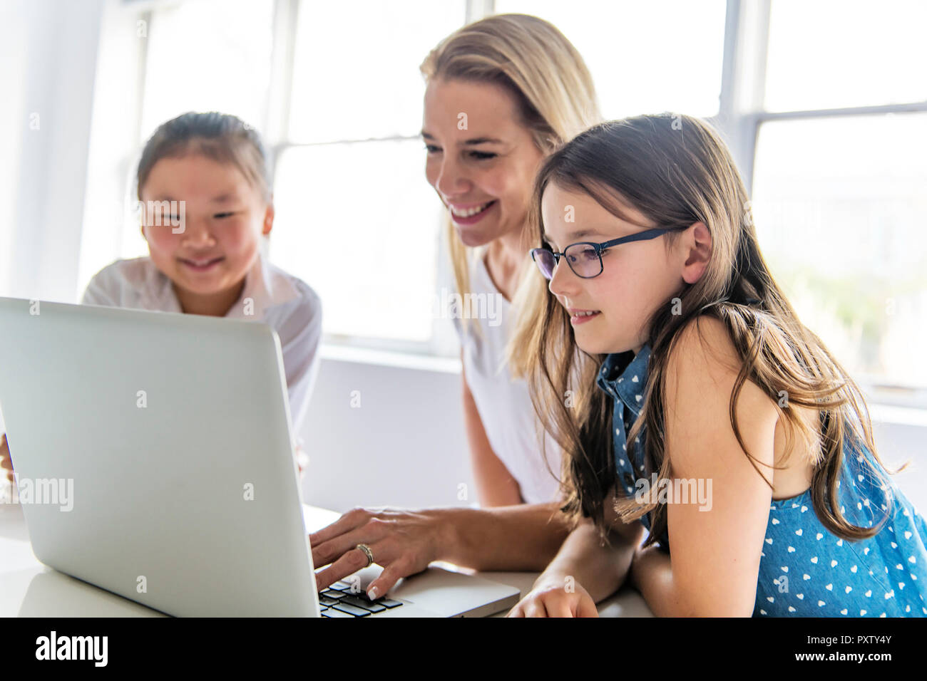A child with technology tablet and laptop computer in classroom teacher ...