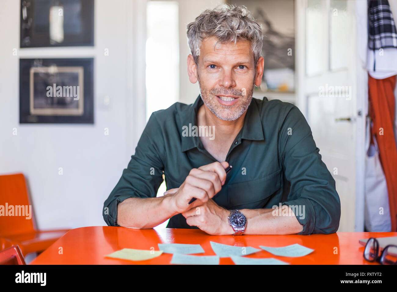 Portrait of mature man sitting at table with notepads Stock Photo