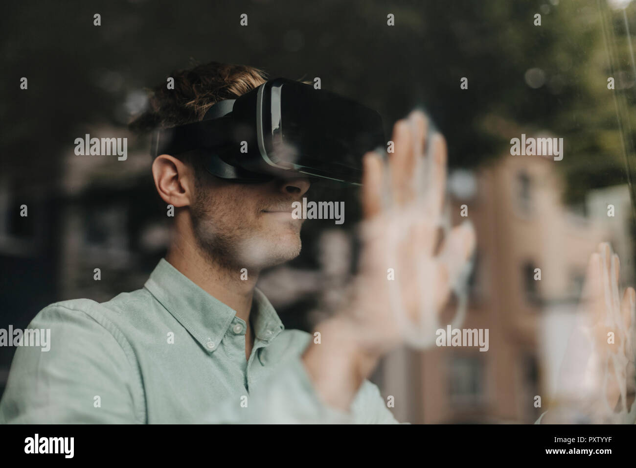 Young man standing at the window, using VR glasses Stock Photo