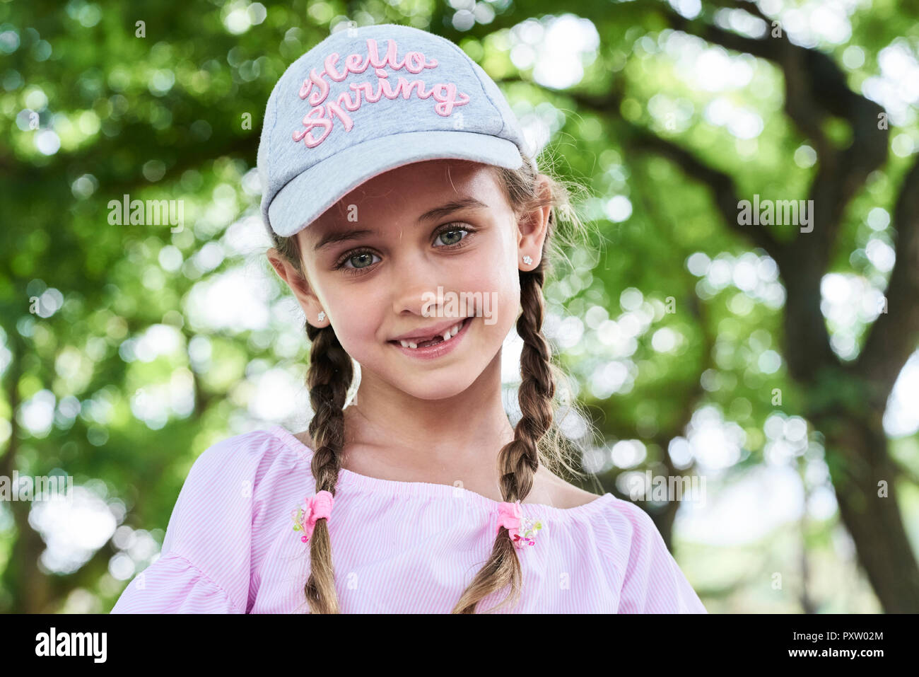 Portrait of little girl with green eyes braids and cap, smiling Stock Photo