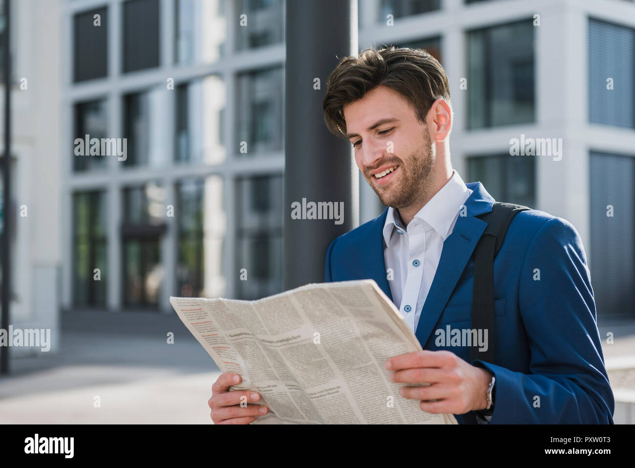 Smiling businessman reading newspaper in the city Stock Photo