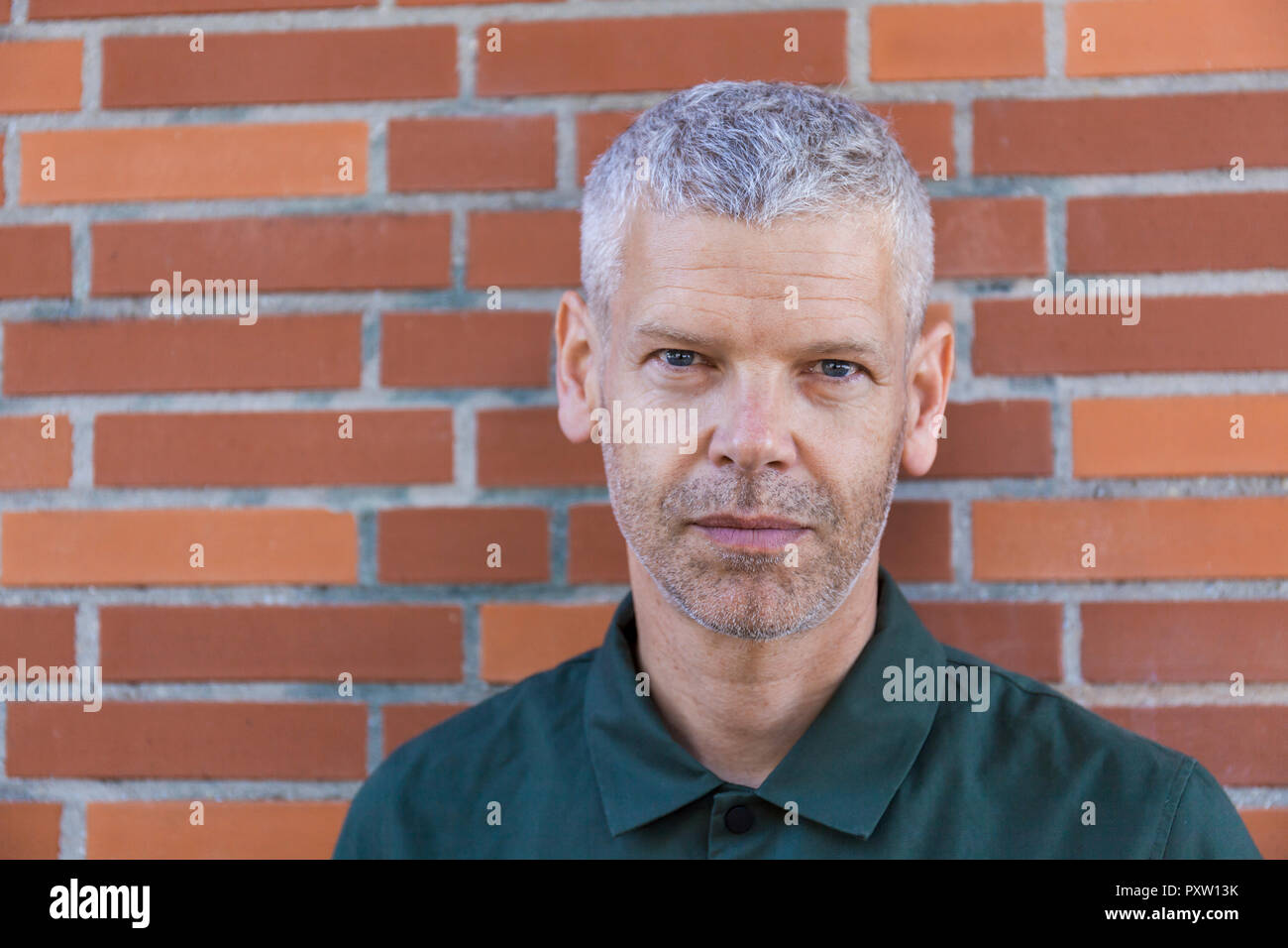 Portrait of a mature man at brick wall Stock Photo