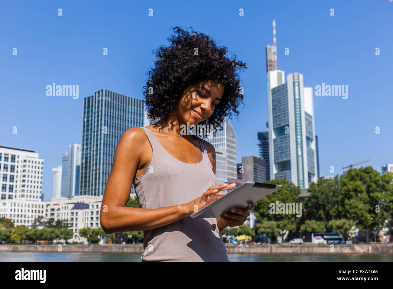 Germany, Frankfurt, smiling young woman using tablet in the city Stock Photo
