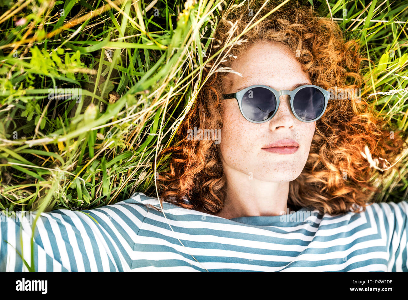 Portrait of young woman relaxing on a meadow wearing sunglasses Stock Photo