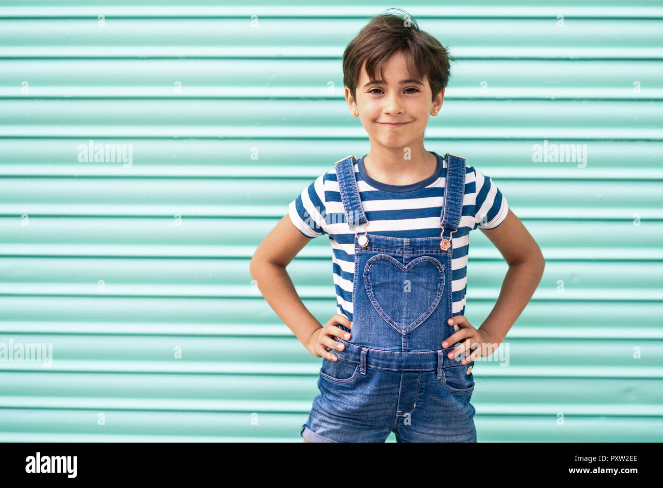Portrait of smiling little girl wearing dungarees Stock Photo