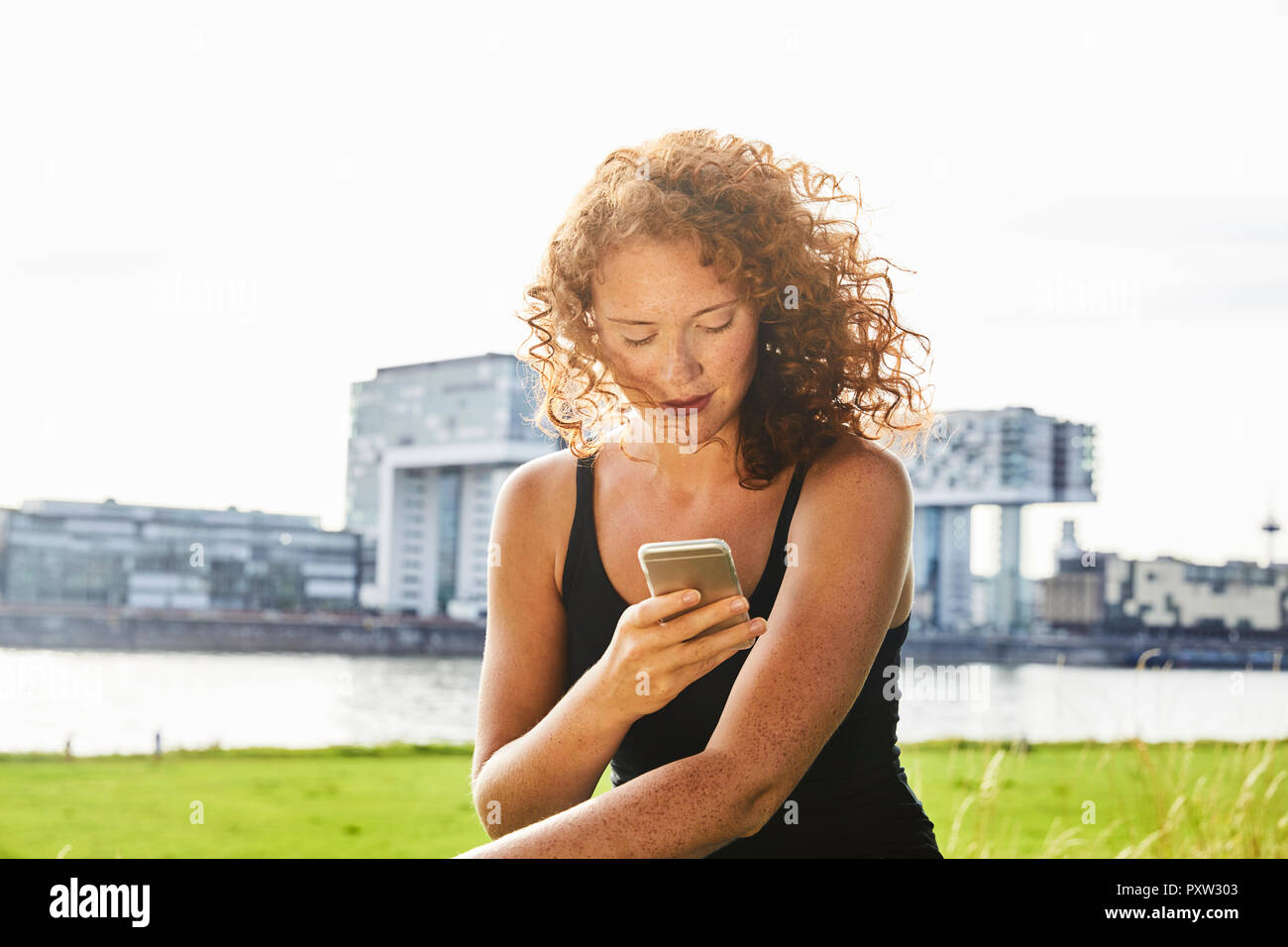 Germany, Cologne, redheaded young woman using cell phone Stock Photo