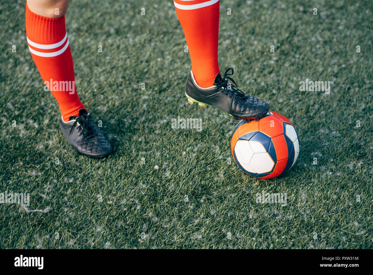 Legs of a woman standing on football ground with the ball Stock Photo