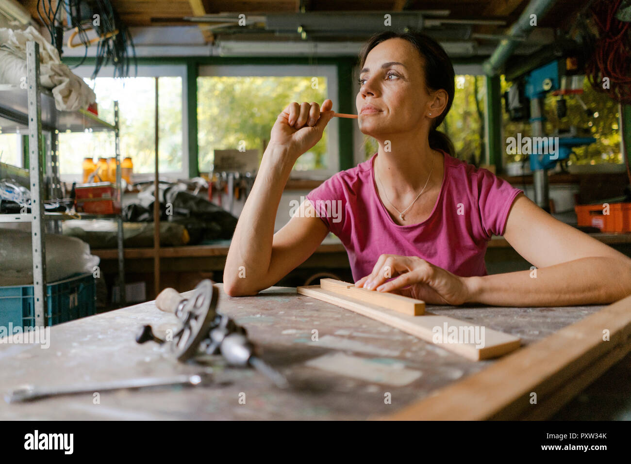 Mature woman at workbench in her workshop thinking Stock Photo