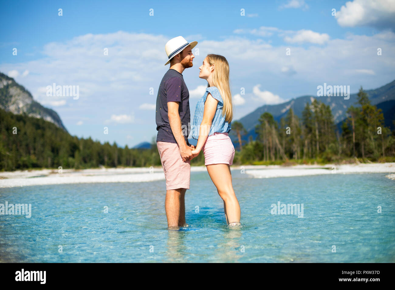 Young couple standing in water, holding hands Stock Photo
