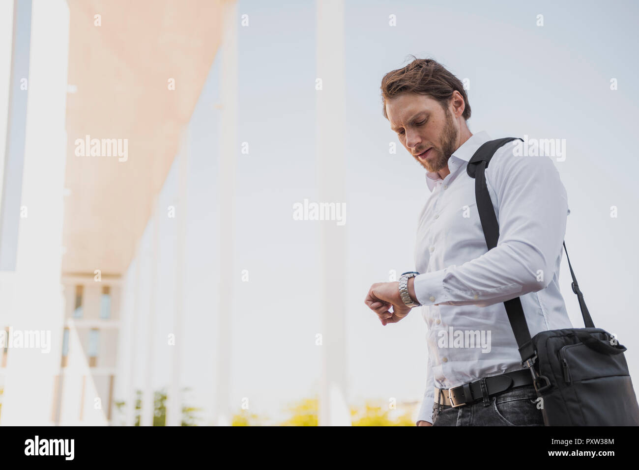 Businessman with laptop bag on the move checking the time Stock Photo