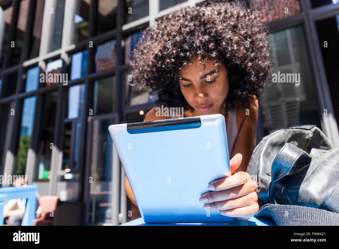 Young woman with curly using tablet in the city Stock Photo
