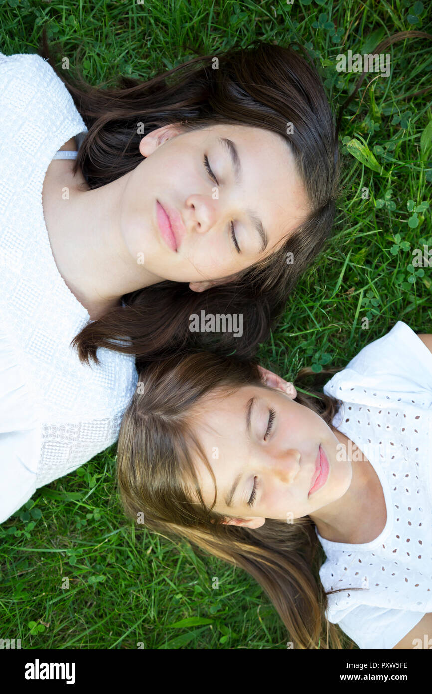 Two sisters resting together on a meadow Stock Photo