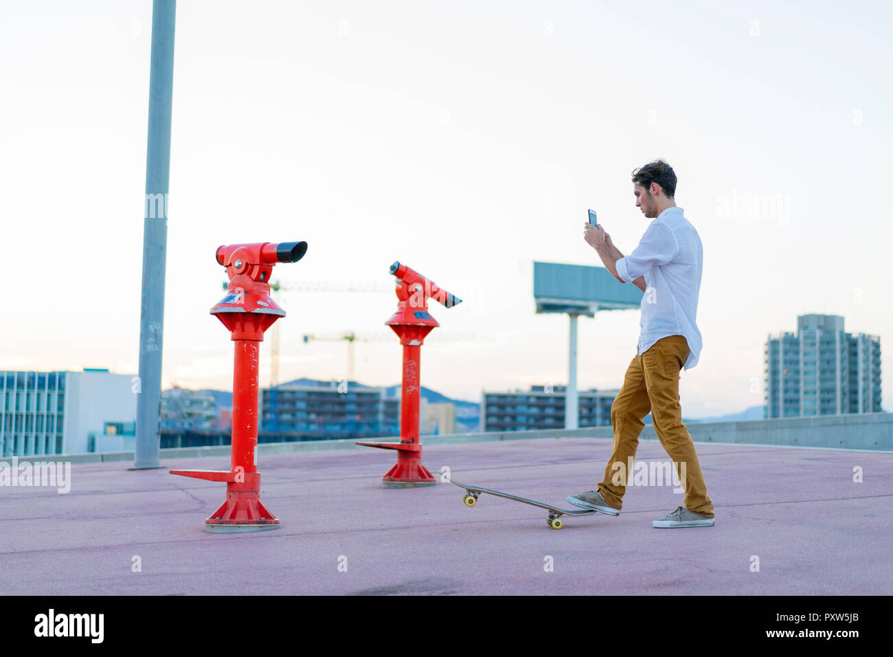 Young man with a skateboard using cell phone Stock Photo