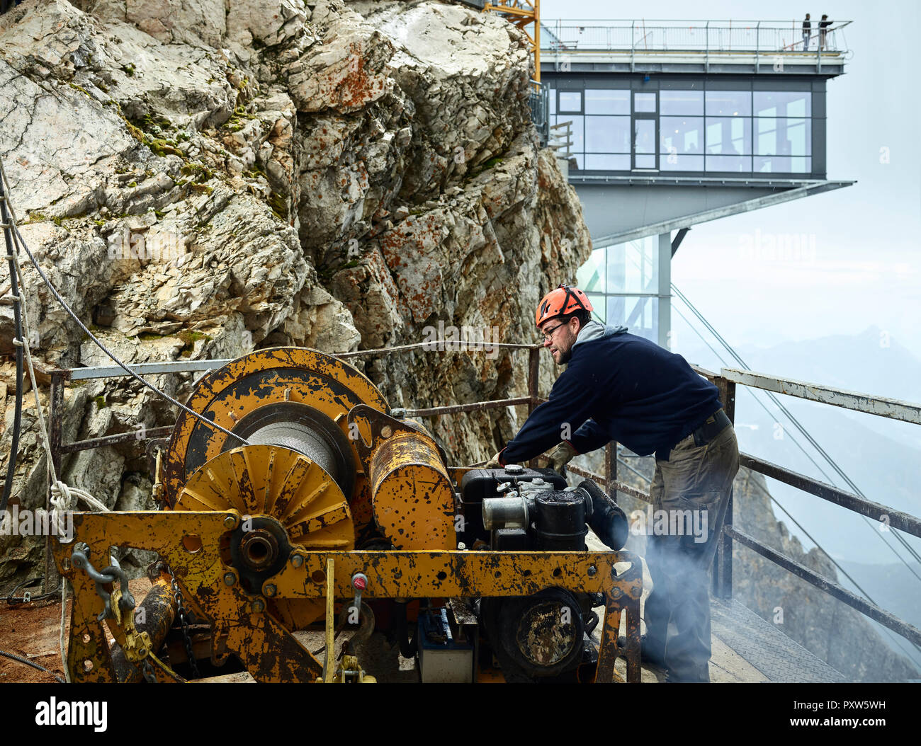 Germany, Bavaria, Garmisch-Partenkirchen, Zugspitze, installer working with rope pulley on goods cable lift Stock Photo
