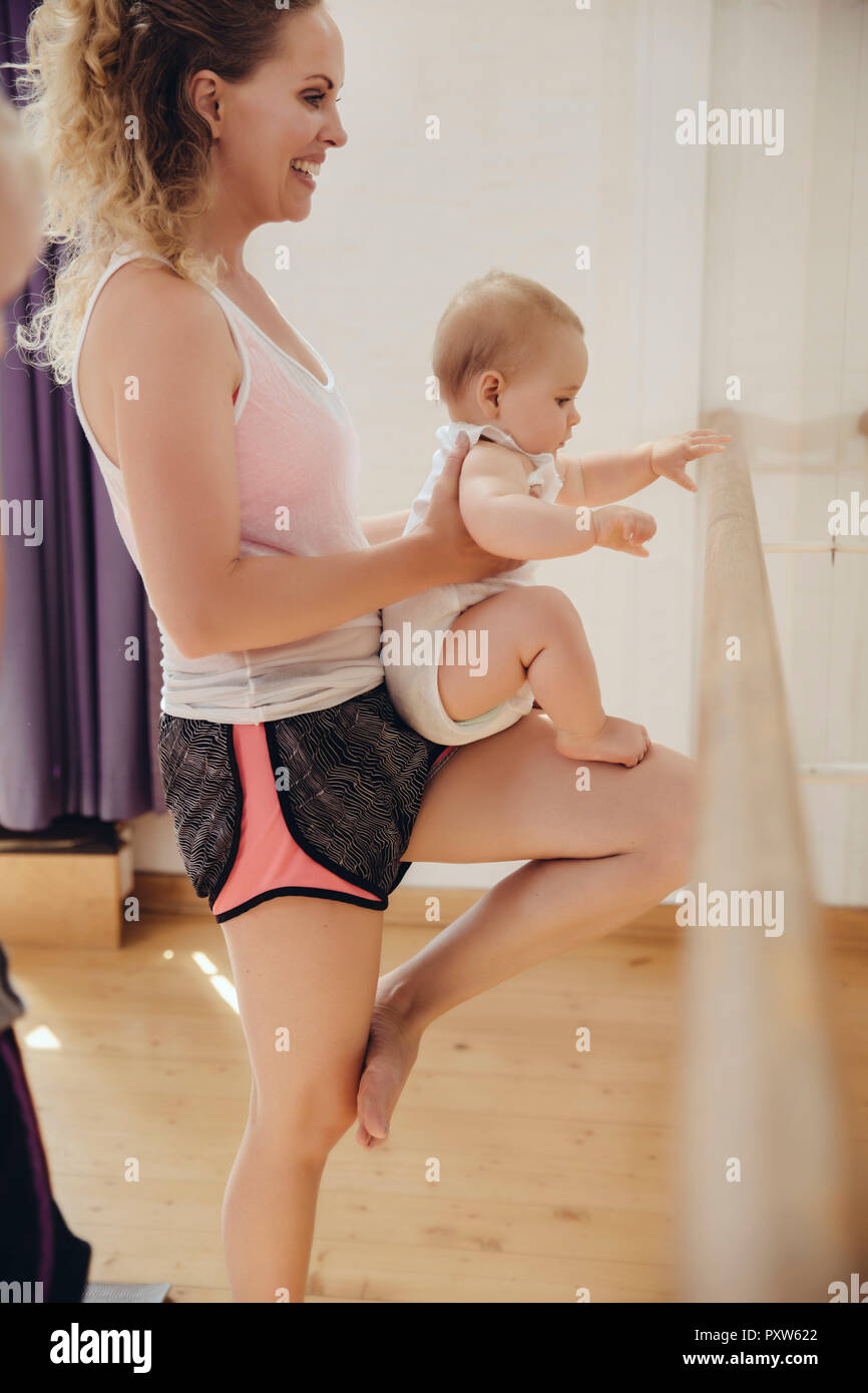 Two mothers holding up their small children to barre in dance studio Stock Photo