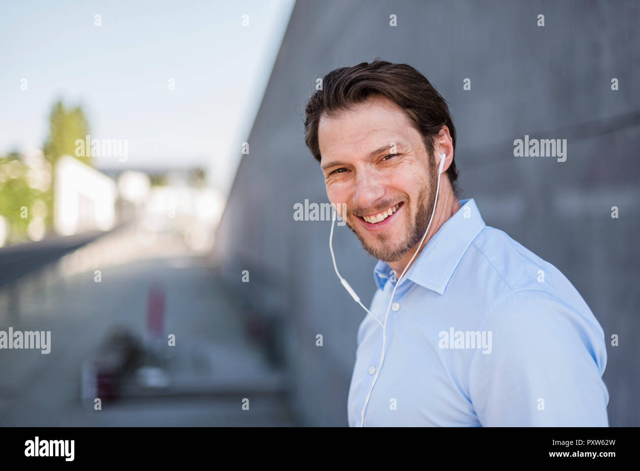 Portrait of smiling businessman wearing earbuds Stock Photo