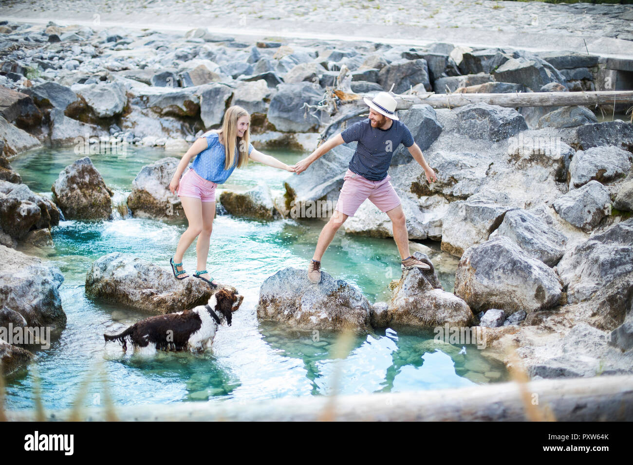 Young couple crossing river Stock Photo
