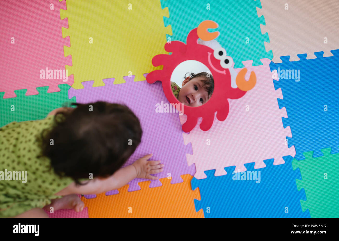 Cute Baby Girl Looking At Herself In A Toy Mirror On A