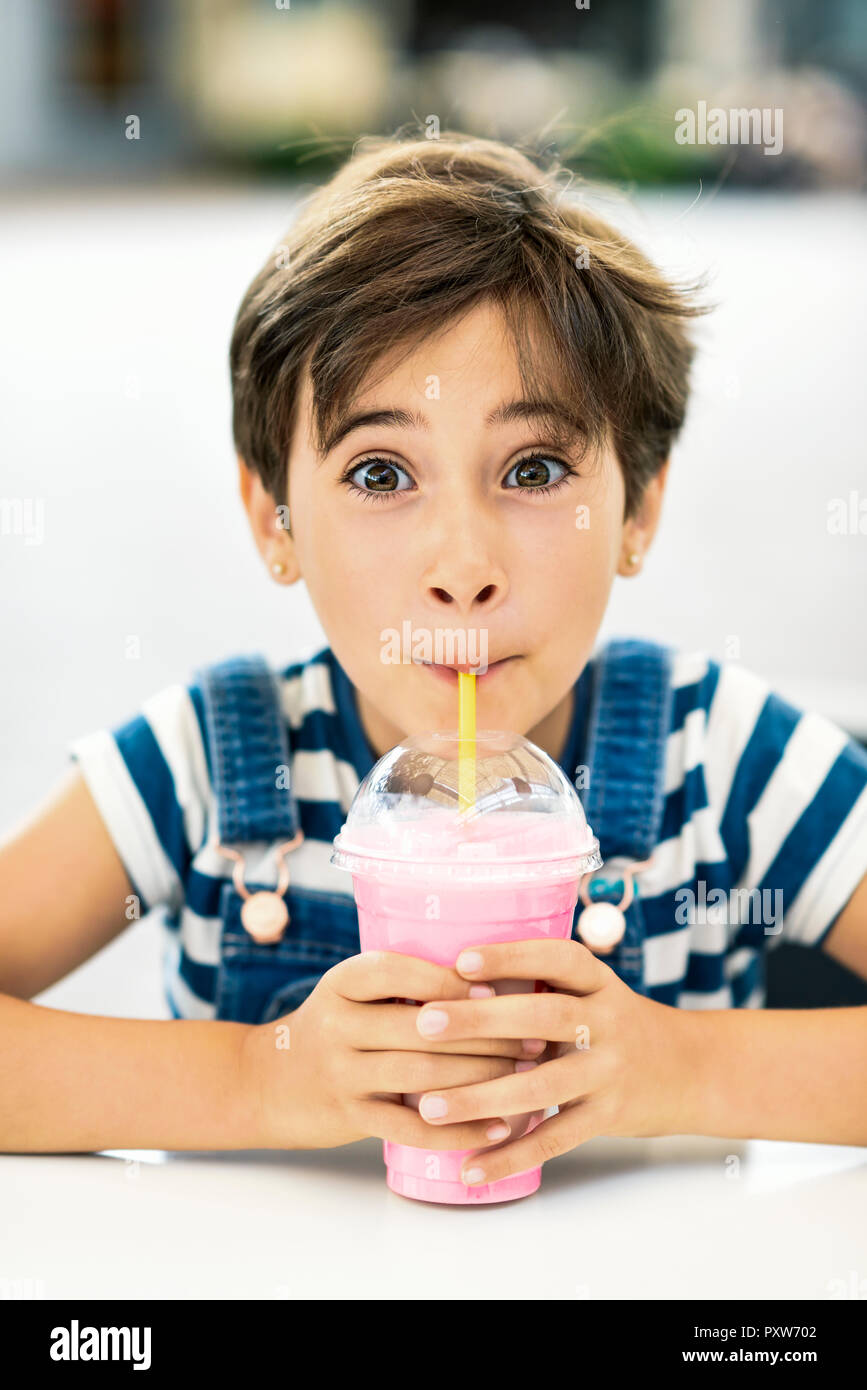 Portrait of little girl drinking strawberry milkshake at pavement cafe Stock Photo