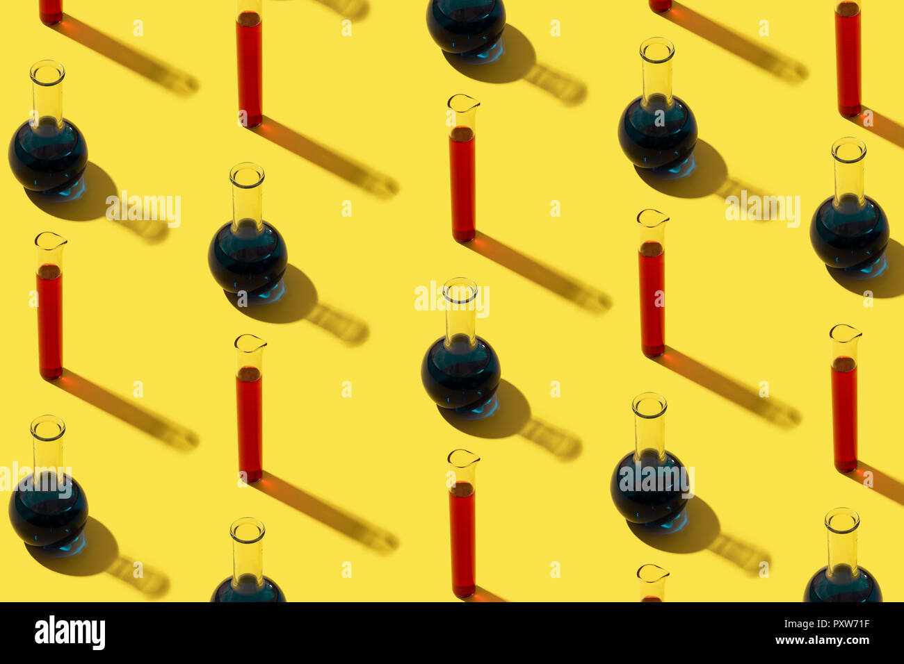 Row of test tubes with liquid, yellow background Stock Photo