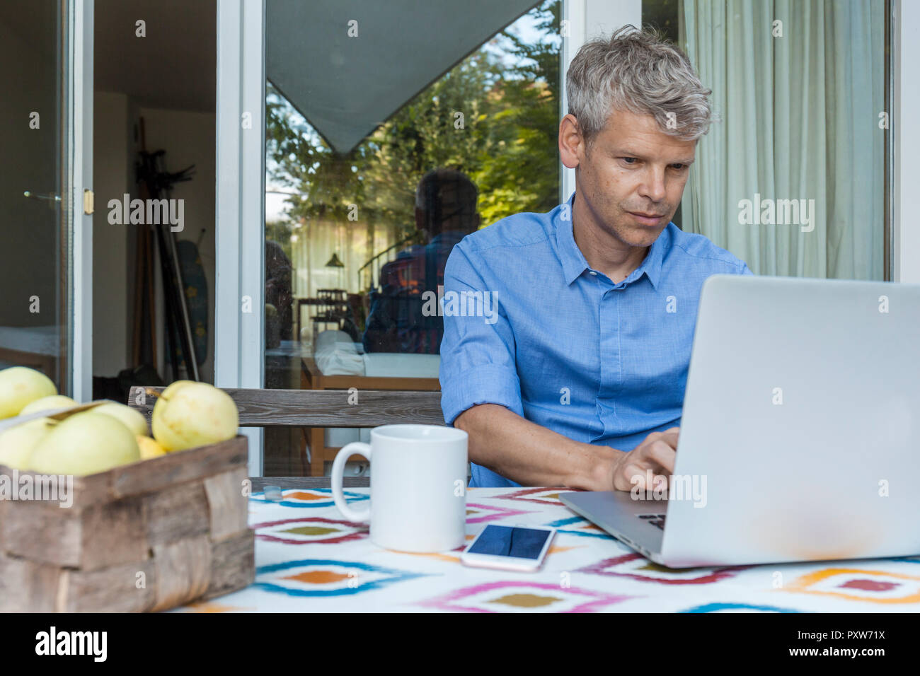 Portrait of mature man using laptop on terrace Stock Photo