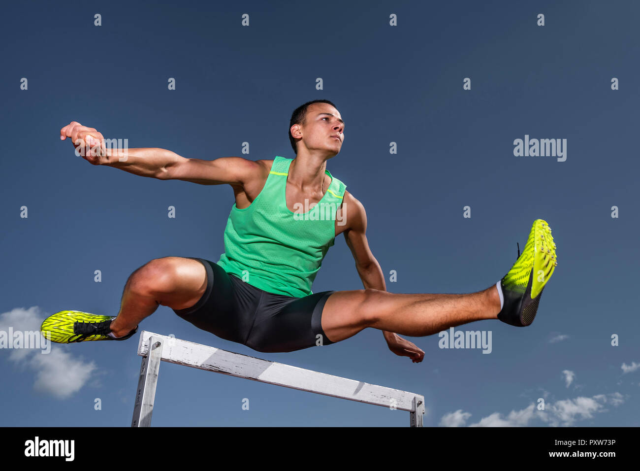 Young runner crossing hurdle Stock Photo