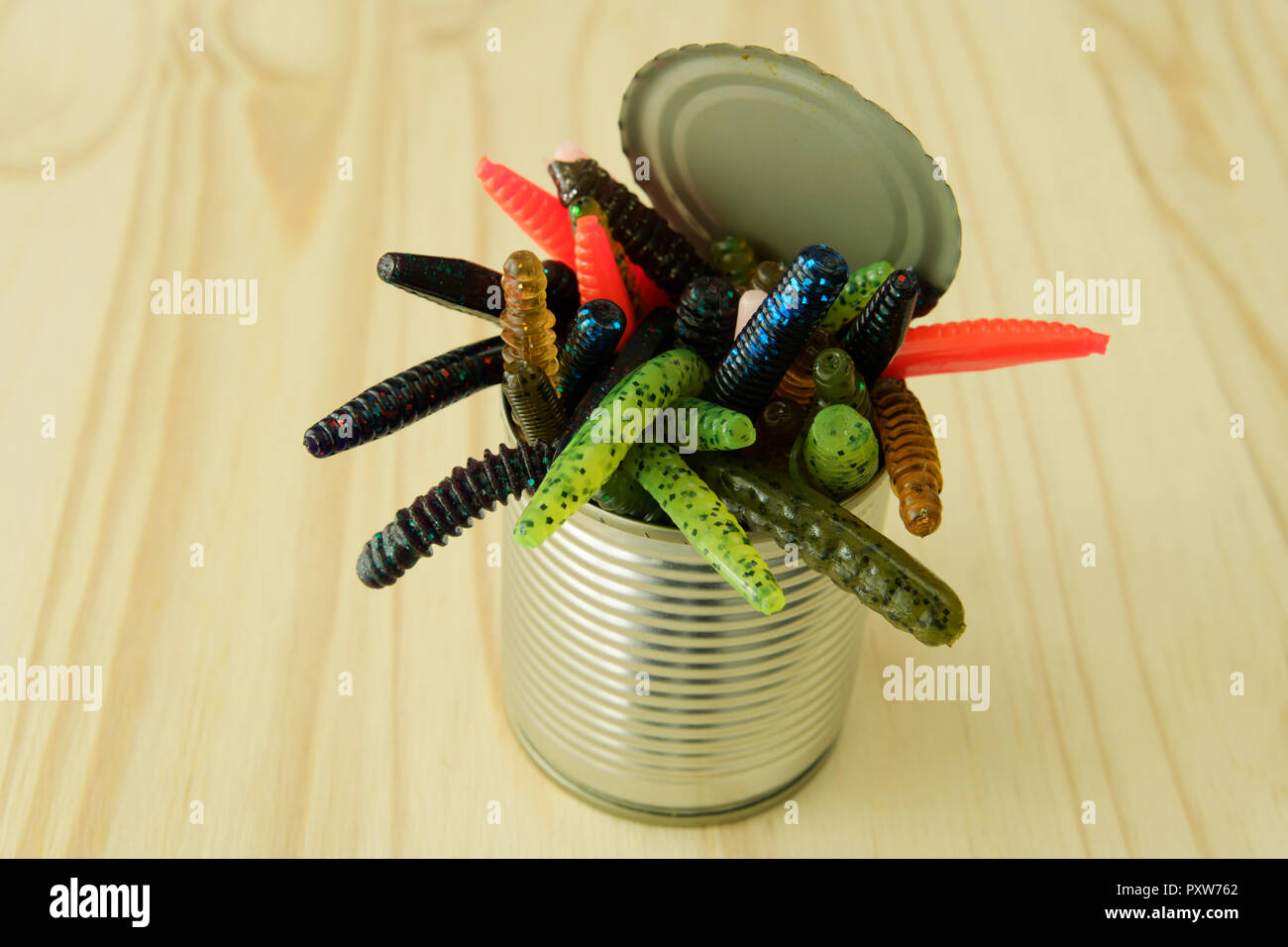 Close-up, detail, opening can of worms, artificial plastic worm-like creatures crawling out of tin on wooden background, objects Stock Photo