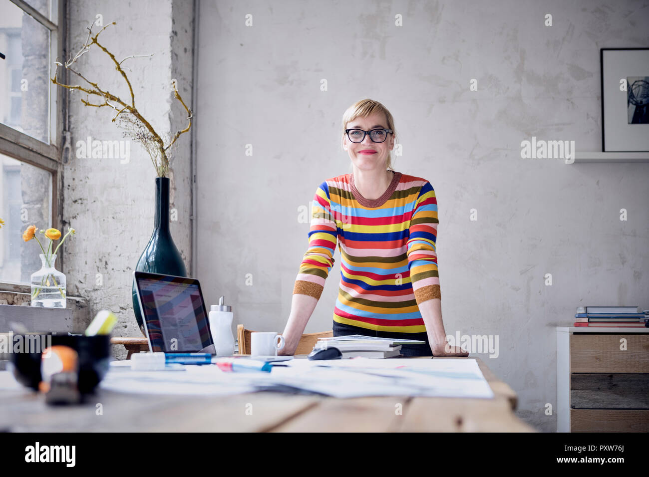 Portrait of smiling woman at desk in a loft Stock Photo