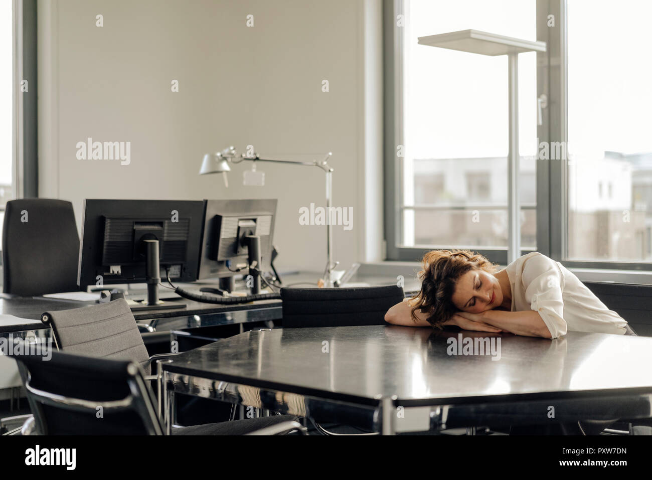 Tired businesswoman sleeping on her desk Stock Photo