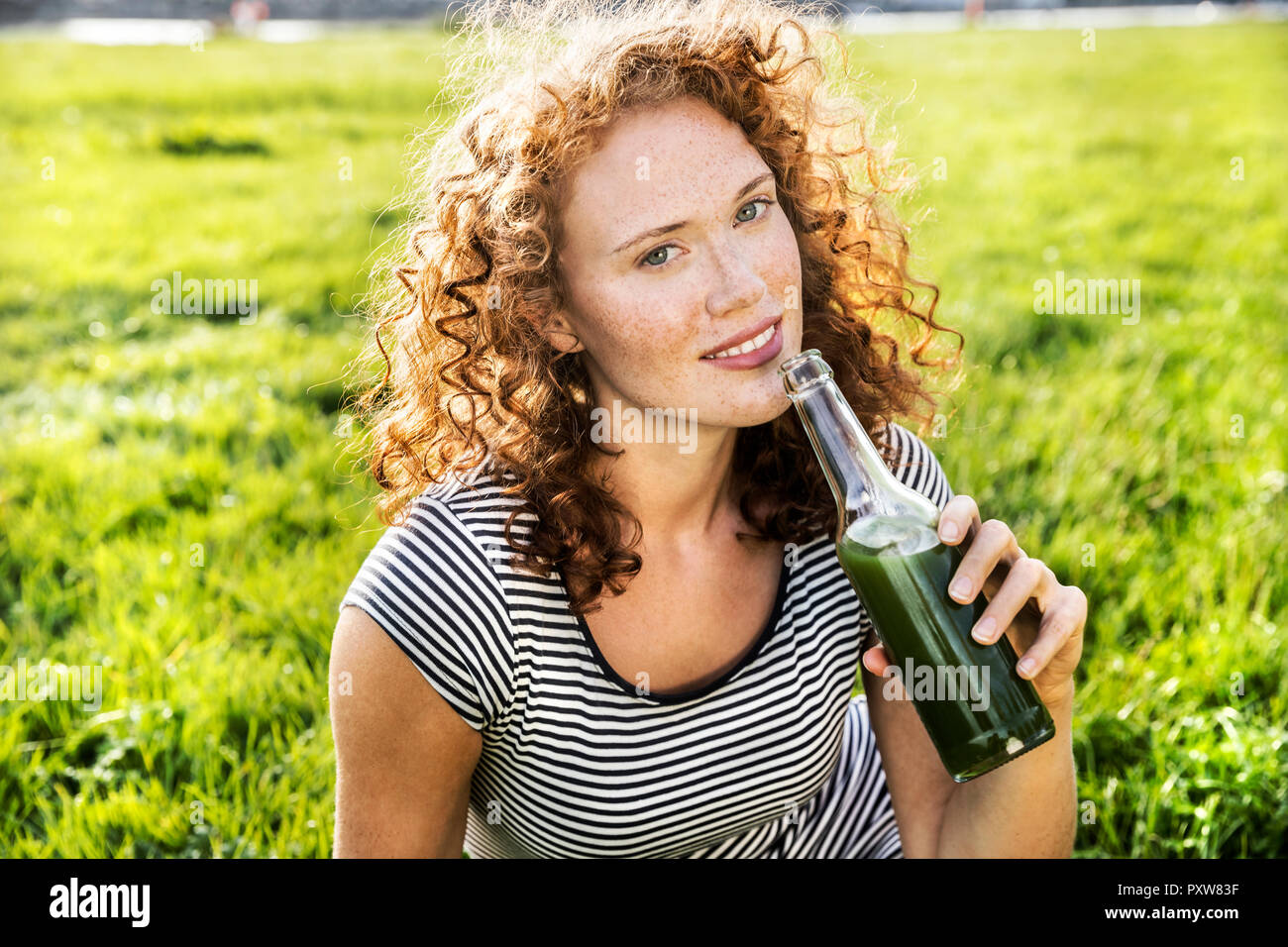 Portrait of redheaded young woman enjoying beverage Stock Photo