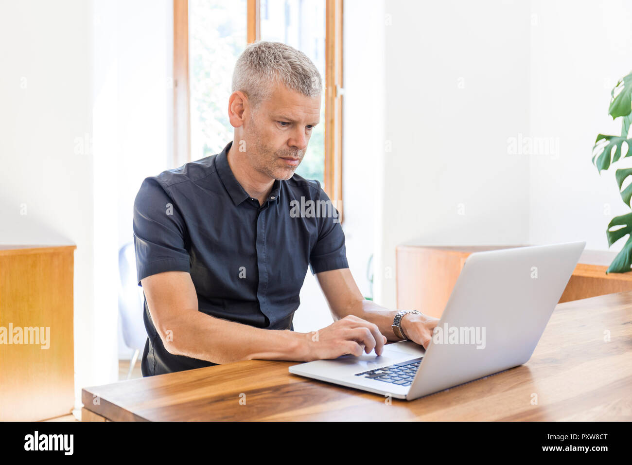 Mature man using laptop on wooden table Stock Photo