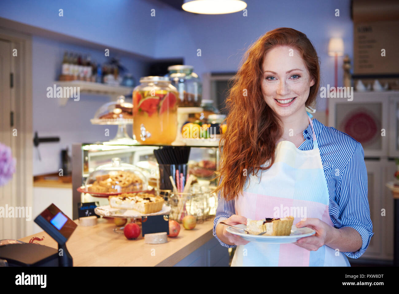 Portrait of smiling young woman serving cake in a cafe Stock Photo