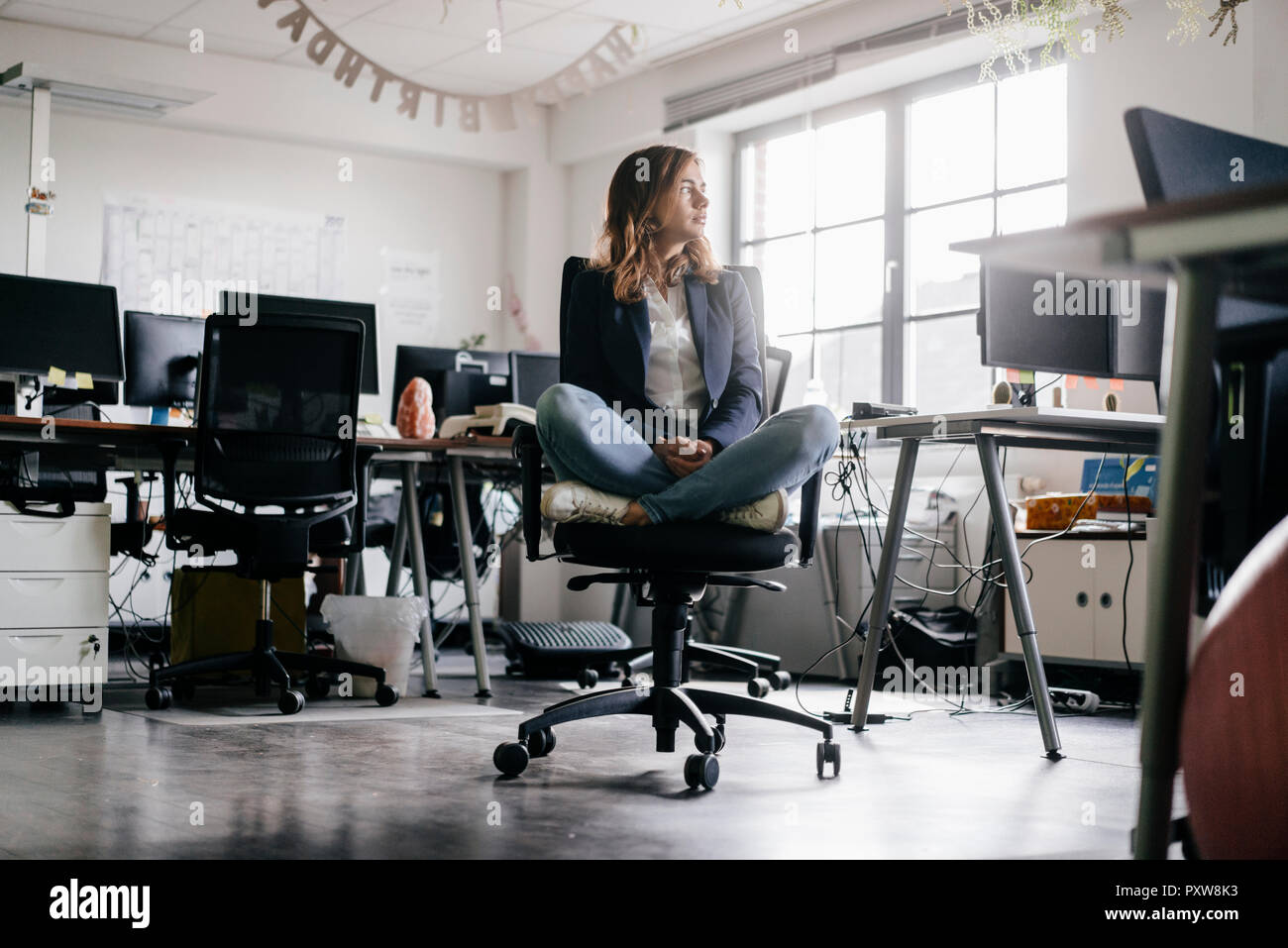 Businesswoman Sitting Cross Legged On An Office Chair Stock Photo