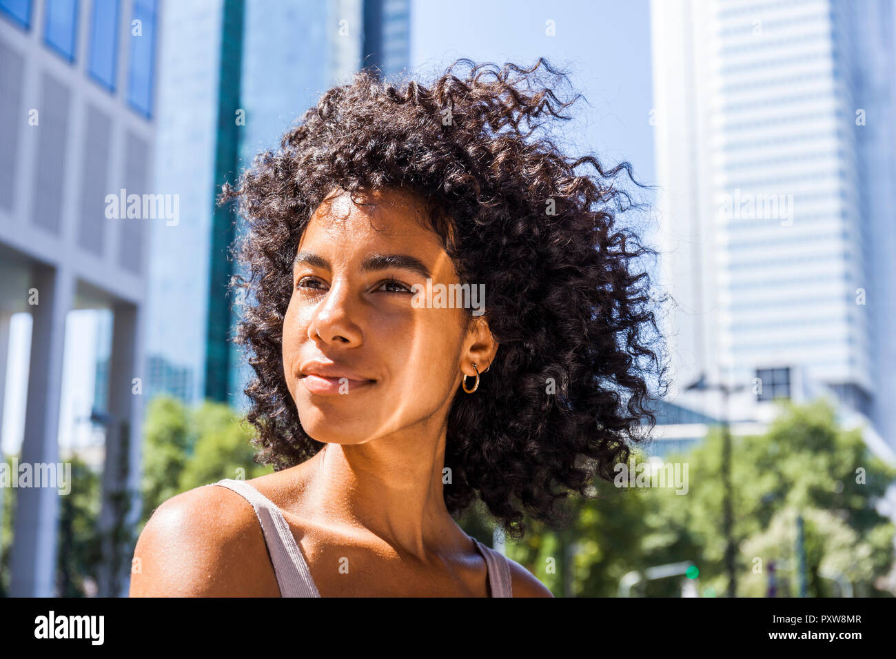 Germany, Frankfurt, portrait of content young woman with curly hair Stock Photo