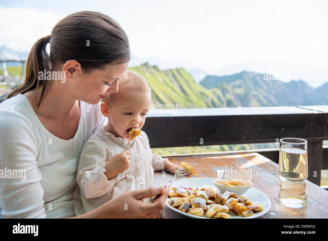 Germany, Bavaria, Oberstdorf, mother and little daughter having lunch at a mountain hut Stock Photo