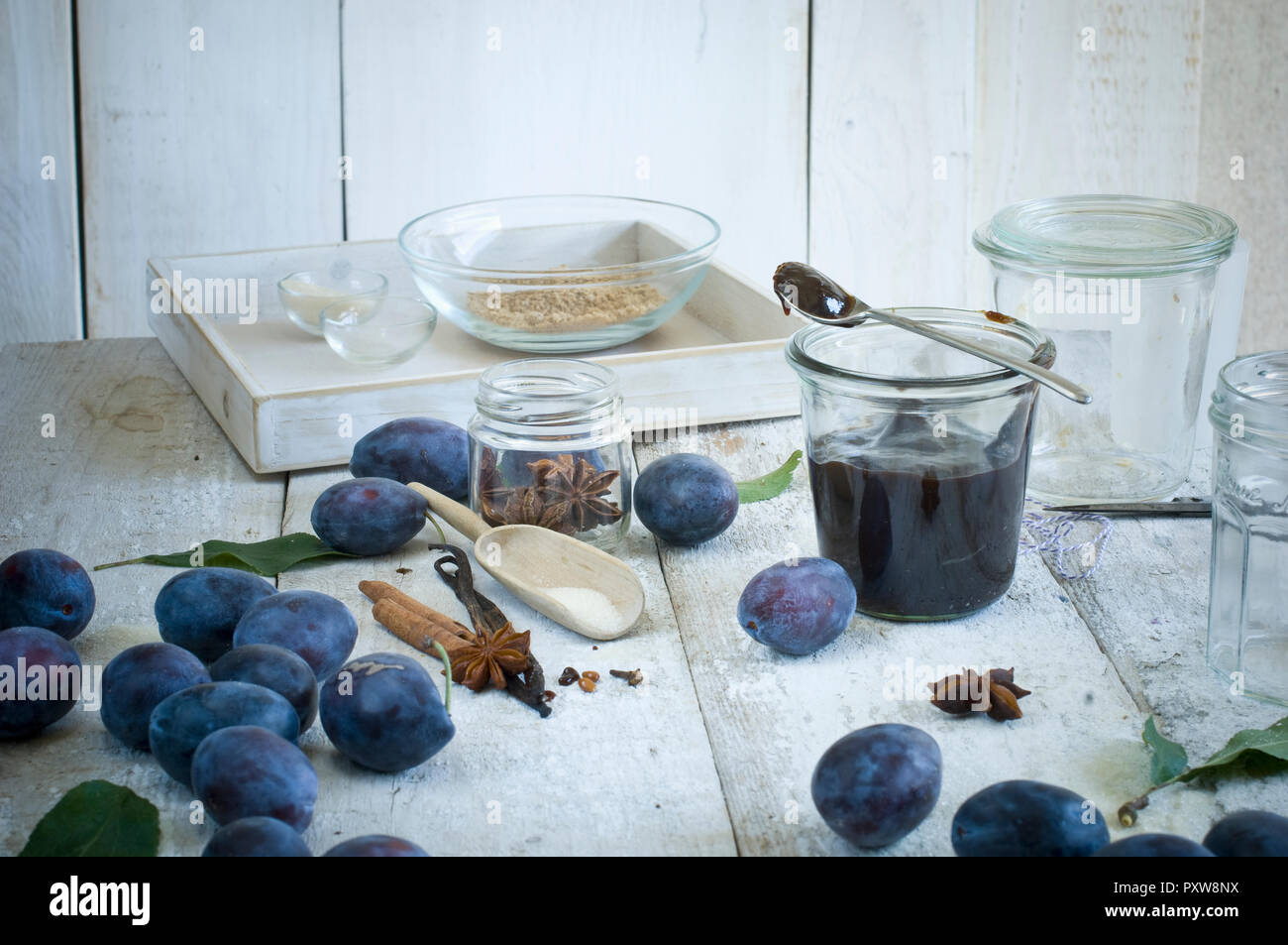 Preserving jar of plum jam and ingredients on wood Stock Photo