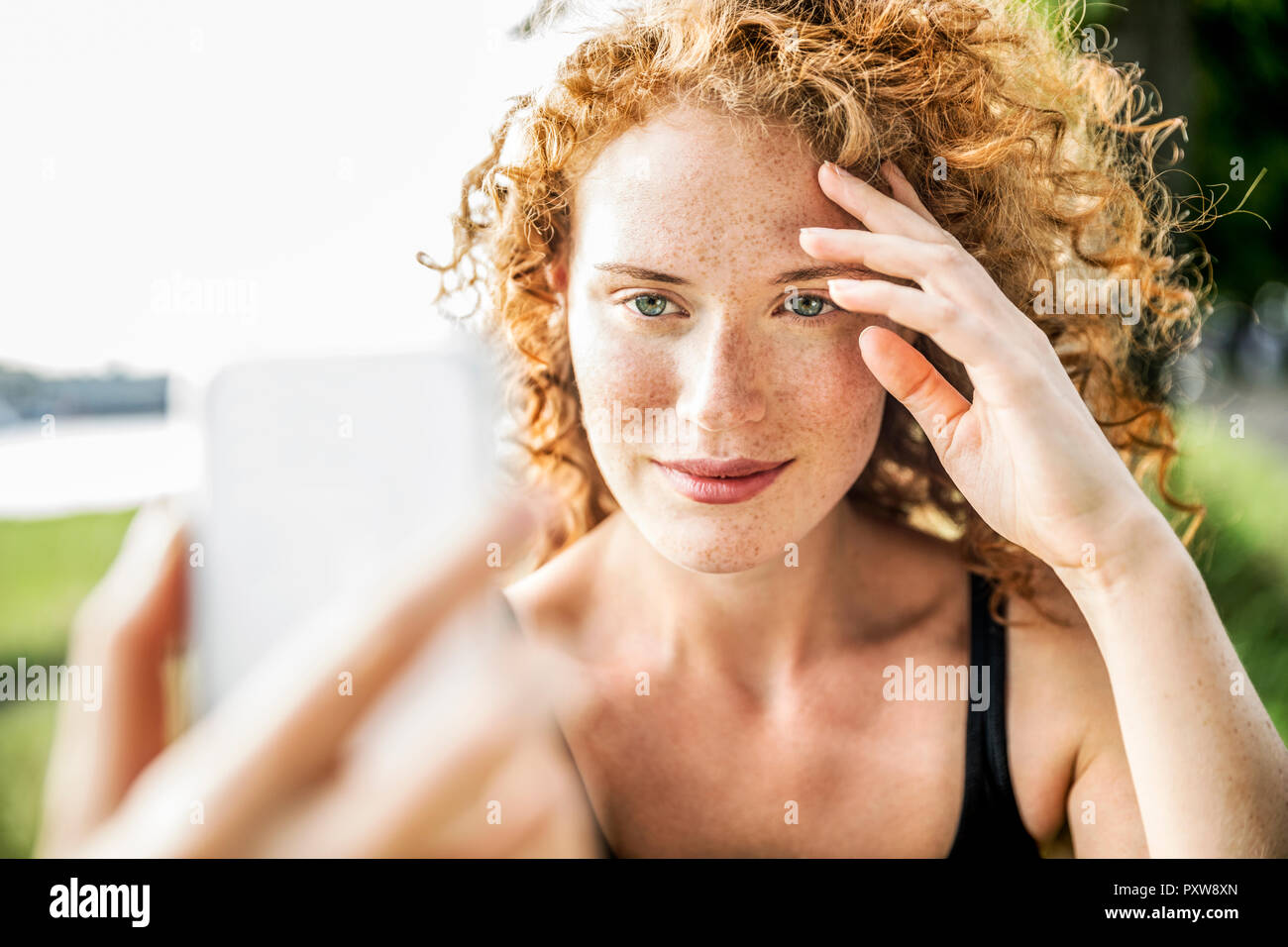 Portrait of freckled young woman taking selfie with cell phone Stock Photo
